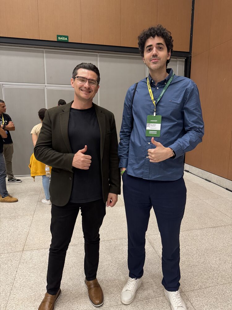 Ricardo e outro participante, de crachá, no saguão do evento
