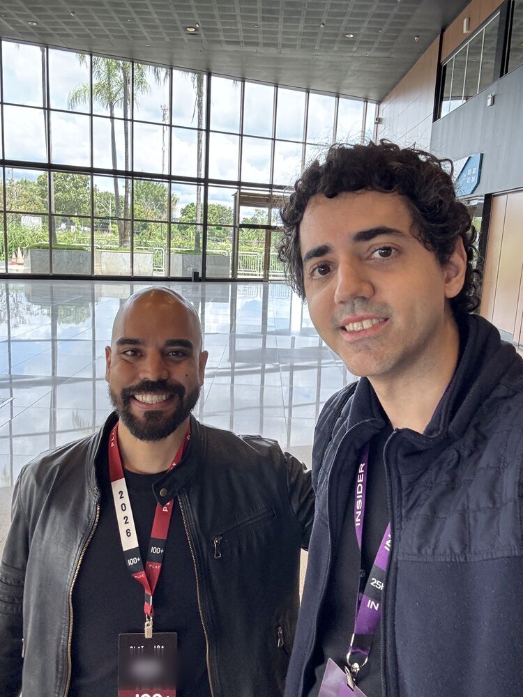 Ricardo e outro participante, de crachá, no saguão do evento